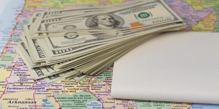 Money stacks, land deed, Arkansas map.